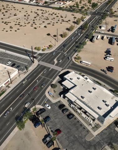 Aerial view of the Cesar Chavez Boulevard Improvements project showing a redesigned multi-lane intersection, updated crosswalks, traffic flow improvements, parking areas, and surrounding desert landscape.
