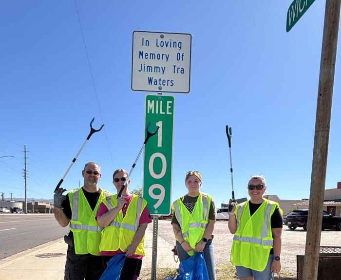 A group of people in safety jackets standing in front of a sign