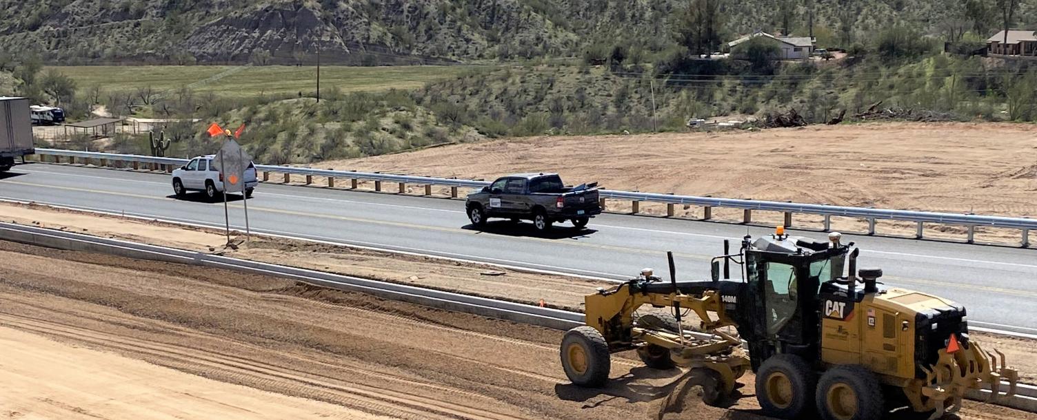 A grader spreads aggregate base course on the future northbound lanes as work progresses on the US 93 widening project in Wickenburg. The base course, which serves as the sub-base layer of an asphalt roadway, is spread and compacted to provide a stable base for pavement. Paving of the new northbound lanes is scheduled to begin in March. (Photo courtesy of ADOT)